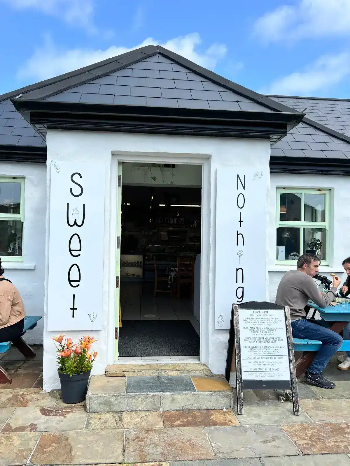 Cafe entrance with menu board and people dining al fresco